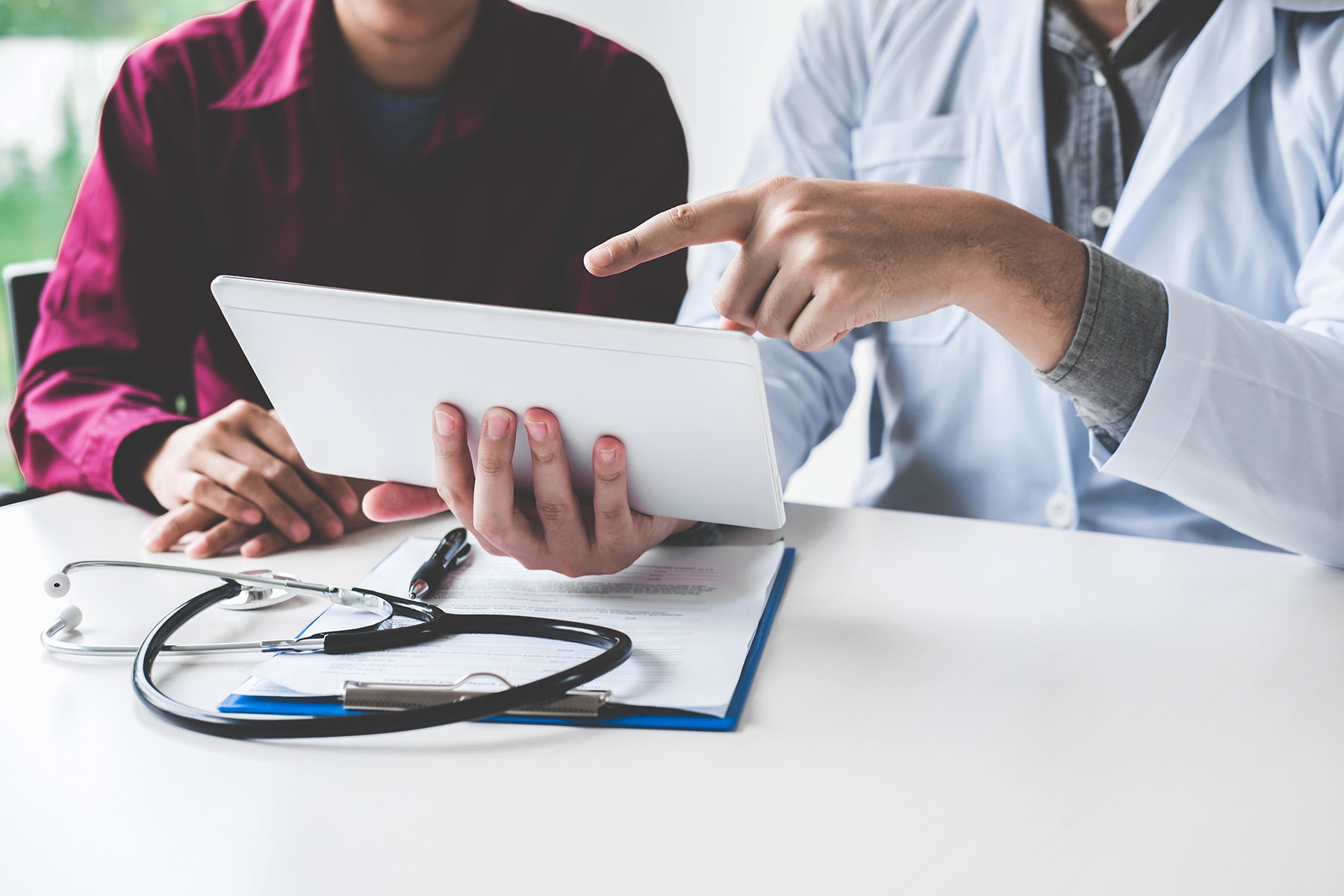 web_midsection-doctor-explaining-patient-digital-tablet-table
